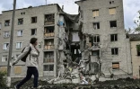 Une femme passe devant un immeuble éventré à Bakhmut, dans l'est de l'Ukraine, le 22 mai 2022