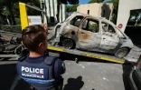 Un policier devant une voiture brûlée placée sur la plateforme d'un véhicule de remorquage à La Grande Motte, deux jours après l'attentat contre une synagogue, le 26 août 2024 dans l'Hérault