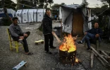 Des hommes se réchauffent autour d'un feu de bois dans le camp de réfugiés de Moria sur l'île grecque de Lesbos, le 19 mars 2019