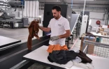 Un employé place des vêtements usagés sur une machine de tri sur le site du Cetia à Hendaye, dans les Pyrénées-Atlantiques, le 4 septembre 2023