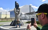 Des touristes se photographient devant la la nouvelle chape recouvrant le 4e réacteur accidenté de la centrale de Tchernobyl le 23 avril 2018