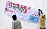 Un manifestant accroche une banderole "grande grève climatique" à l'occasion de la mobilisation pour le climat, le 20 septembre 2019 à Thiès, au Sénégal