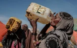 Une femme boit après une distribution d'eau dans le camp de déplacés de Muuri à Baidoa (Somalie) le 13 février 2022