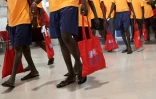 Des migrants portant des sacs de l'Offiche français de l'immigration et l'intégration arrivent à l'aéroport de Roissy-Charles-de-Gaulle en juillet 2018, près de Paris