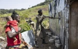 Famata Turay (g), son fils Ibrahim Sanko dans les bras, regarde un garde-forestier de l'Autorité nationale des aires protégées (NPAA) détruire sa maison de tôle illégale, située au sein du Parc national de la Péninsule de la Région Ouest, le 22 avril 2025 en Sierra Leone