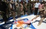 Sur cette photo d'archive, des combattants chiites irakiens des brigades du Hezbollah brûlent des drapeaux américains et israéliens durant un défilé militaire à Bagdad, le 31 mai 2019