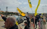 Des habitants brandissent des drapeaux du Hezbollah tandis que des personnes déplacées rentrent chez elles en voiture dans la région d'Habbouch, dans le sud du Liban, le 17 avril 2026