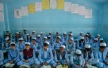 Des élèves en shalwar kameez et chapeaux blancs, selon le nouveau code d'uniforme, le 22 avril 2025 à Kandahar, en Afghnistan