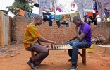 Robert Katende (g) et  Brian Mugabi (d), respectivement coach et frère de Phiona Mutesi, jouent aux échecs, au club  d'échecs de Katwe, banlieue de Kampala, le 29 septembre 2016 
