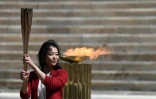 L'ancienne nageuse japonaise Imoto Naoko s'empare de la flamme olympique lors de la cérémonie de sa passation entre la Grèce et le Japon dans un stade pathénaïque vide, le 19 mars 2020 à Athènes