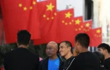 Des employés discutent après avoir installé des drapeaux de la Chine devant un centre commercial à Lankao, dans la province du Henan (centre), le 28 septembre 2017