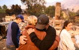 Les membres d'une famille s'étreignent en regardant les restes brûlés de leur maison dans l'incendie d'Eaton dans la région d'Altadena, dans le comté de Los Angeles, en Californie, le 9 janvier 2025