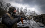 Un militaire ukrainien tient un fusil dans une tranchée près de Kharkiv le 31 mars 2022