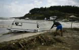 Un homme déblaie les débris près d'une caravane échouée au bord de la mer Noire, au camping d'Aravia près de Tsarevo en Bulgarie le 6 septembre 2023