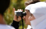 Un jeune homme druze regarde avec une paire de jumelles des proches fuyant les violences près de Damas, après leur arrivée dans la zone tampon en face du village de Majdal Shams sur les hauteurs de la partie du Golan occupée par Israël, le 3 mai 2025
