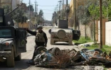 Un membre des forces de la coalition près d'un char détruit  lors d'un raid visant le groupe EI le 26 mars 2017 dans le quartier al-Jadida à Mossoul  