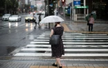 Une femme se protège de la pluie avec son parapluie à Tokyo le 28 juillet 2018 avant l'arrivée du typhon Jongdari