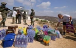 Des soldats israéliens devant l'entrée d'une maison palestinienne assiégée par des colons israéliens dans le village de Qusra, au sud de Naplouse, alors que des militants de gauche israéliens déposent des vivres pour ses habitants, le 14 août 2026 en Cisjordanie occupée