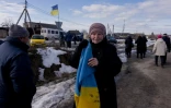 Une femme tient un drapeau ukrainien pour accueillir un convoi de soldats libérés par les Russes après un échange de prisonniers, le 6 mars 2026 dans un lieu non précisé dans le nord de l'Ukraine