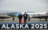 Le président américain Donald Trump et le président russe Vladimir Poutine debout sur un podium sur le tarmac après être arrivés à la base militaire Elmendorf-Richardson en Alaska, le 15 août 2025