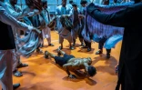 Des hommes utilisent leurs écharpes pour rafraîchir un culturiste afghan qui s'échauffe dans les coulisses avant de participer au concours de Mr. Afghanistan, le 10 juillet 2024 à Kaboul