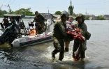 Des militaires ukrainiens portent un habitant handicapé lors de l'évacuation d'une zone inondée à Kherson le 8 juin 2023