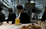 Des clients du bar Gomi Pit à Tokyo se restaurent en contemplant l'action de la grosse pince en train de secouer des déchets, le 18 janvier 2019