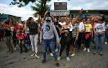 Des membres de famille de détenus saluent au passage d'un autobus effectuant un transfert de prisonniers aprè sla reprise du contrôle de la prison de Tocoron, dans l'État d'Aragua, au Venezuela, le 20 septembre 2023