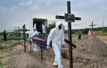 Des employés municipaux transportent des sacs mortuaires, dans un cimetière de la ville de Boutcha, dans la région de Kyiv, le 11 août 2022