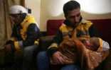 Samir Salim et ses trois frères, tous secouristes des Casques blancs syriens dans la Ghouta orientale, se tiennent aux côtés d'un de leurs collègues tenant un bébé, à Madira, le 12 février 2018