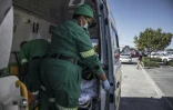 L'ambulancière Inathi Jacob (d) prépare une perfusion pour un jeune patient lors d'une intervention dans le township Philippi, près du Cap, le 17 avril 2025 en Afrique du Sud