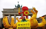 Un militant de Greenpeace devant une dépouille de dinosaure, place de Brandebourg, pour célébrer l'adieu au nucléaire de l'Allemagne, le 15 avril 2023 à Berlin