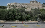 De rares touristes passent au pied de l'Acropole à Athènes, fermée aux heures les plus chaudes de la journée en raison de la "pire canicule" en trente ans en Grèce, le 2 août 2021