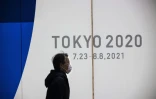 Un piéton passe devant un mur donnant les dates des prochains Jeux Olympiques, décalés à l'été prochain, le 22 janvier 2021 à Tokyo