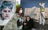 Passantes portant des masques devant une affiche, à Athènes le 4 mai 2020