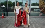 es Chinois Song Jihan (d) et Wang Zengyi montrent le certificat d'enregistrement de leur mariage devant un bureau de district à Bangkok, le 29 mai 2025 en Thaïlande