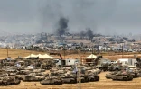 Des tanks et des bulldozers israéliens déployés à la lisière de la bande de Gaza, d'où s'élève de la fumée de bâtiments détruits par des frappes israéliennes, le 17 mai 2025