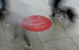 Un autocollant sur le sol appelle à respecter la distanciation physique dans la gare de Munich, en Allemagne, le 25 septembre 2020