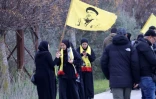 Des habitantes de Kfar Kila portant un drapeau représentant le chef défunt du Hezbollah, tué par Israël, se rassemblent à Borj El Mlouk, dans le sud du Liban, sur une route barrée par l'armée israélienne, le 26 janvier 2025