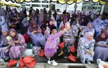 Des habitants attendent de voir passer le cortège du prince Abdul Mateen et son épouse Yang Mulia Anisha Rosnah, le jour de leur mariage, le 14 janvier 2024 à Bandar Seri Begawan, au Brunei
