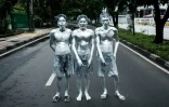 Les artistes de rue Keris Munandar (d), son frère Ari Munandar (c) et leur voisin Riyan Ahmad Fazriyansah dans une rue de Jakarta, le 1er avril 2025 en Indonésie