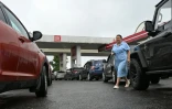 Une femme marche au milieu d'une file de véhicules dans une station-service à Vologda, en Russie, le 14 juillet 2026