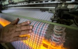 Un employé vérifie la qualité d'un tissu à carreaux dans une usine textile, en Egypte le 29 juillet 2018