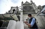 Un tailleur de pierre explique ses gestes Ă des visiteurs devant la basilique Saint-Denis, le 5 juin 2020