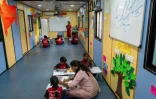Des élèves suivent un cours à "l'école du feu rouge", qui accueille des enfants défavorisés dans des conteneurs aménagés en salles de cours sous un pont autoroutier, le 18 mai 2026 à Bombay