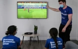 Un animateur donne des instructions à deux filles jouant au jeu vidéo Fifa lors d'un stage gratuit, le 22 juillet 2020 à Boulogne-Billancourt