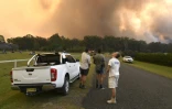 Des habitants observent un incendie près de la localité australienne de Nana Glen, à environ 600 km au nord de Sydney, le 12 novembre 2019