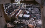 Des Palestiniens se rassemblent pour un repas de rupture du jeûne au milieu des décombres des bâtiments détruits à Beit Lahia, dans le nord de la bande de Gaza, le 15 mars 2025