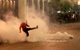 Un manifestant libanais frappe au pied dans une grenade lacrymogène lors de heurts avec des forces de l'ordre dans le centre-ville de Beyrouth, le 15 décembre 2019