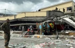 Photo publiée par Michael Thompson, habitant du Vanuatu, montrant un membre des services de sécurité en train d'inspecter les décombres d'un bâtiment détruit par un puissant séisme, à Port-Vila, le 17 décembre 2024